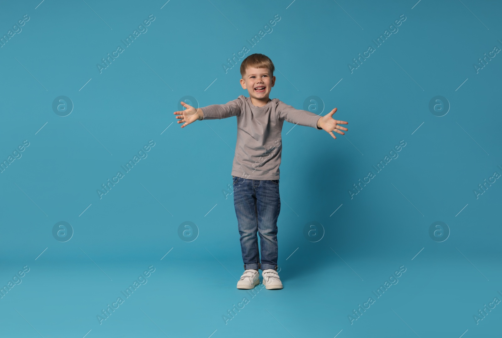 Happy little boy dancing on light blue background Photo of Happy little boy dancing on light blue background