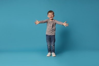 Photo of Happy little boy dancing on light blue background