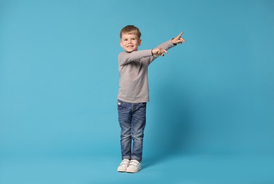 Photo of Happy little boy dancing on light blue background