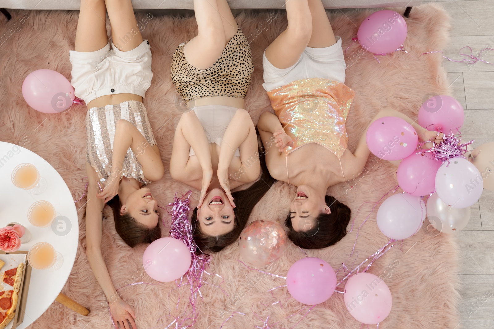 Happy friends with balloons and tinsel on floor at home, top view Photo of Happy friends with balloons and tinsel on floor at home, top view