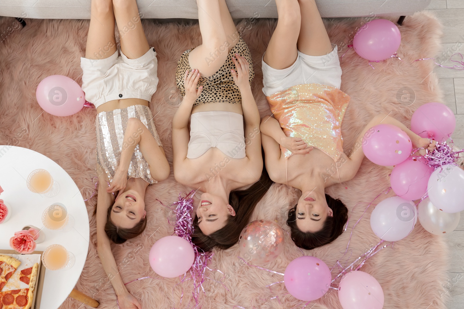 Happy friends with balloons and tinsel on floor at home, top view Photo of Happy friends with balloons and tinsel on floor at home, top view