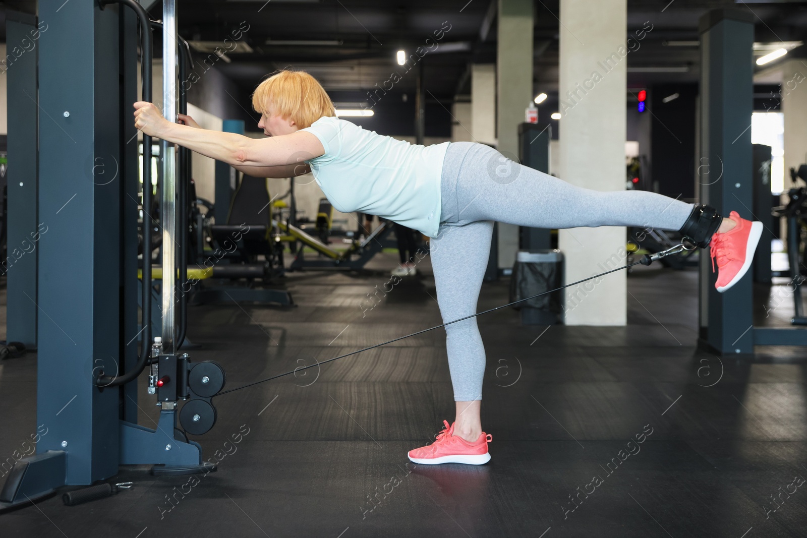 Senior woman training on cable machine in gym Photo of Senior woman training on cable machine in gym
