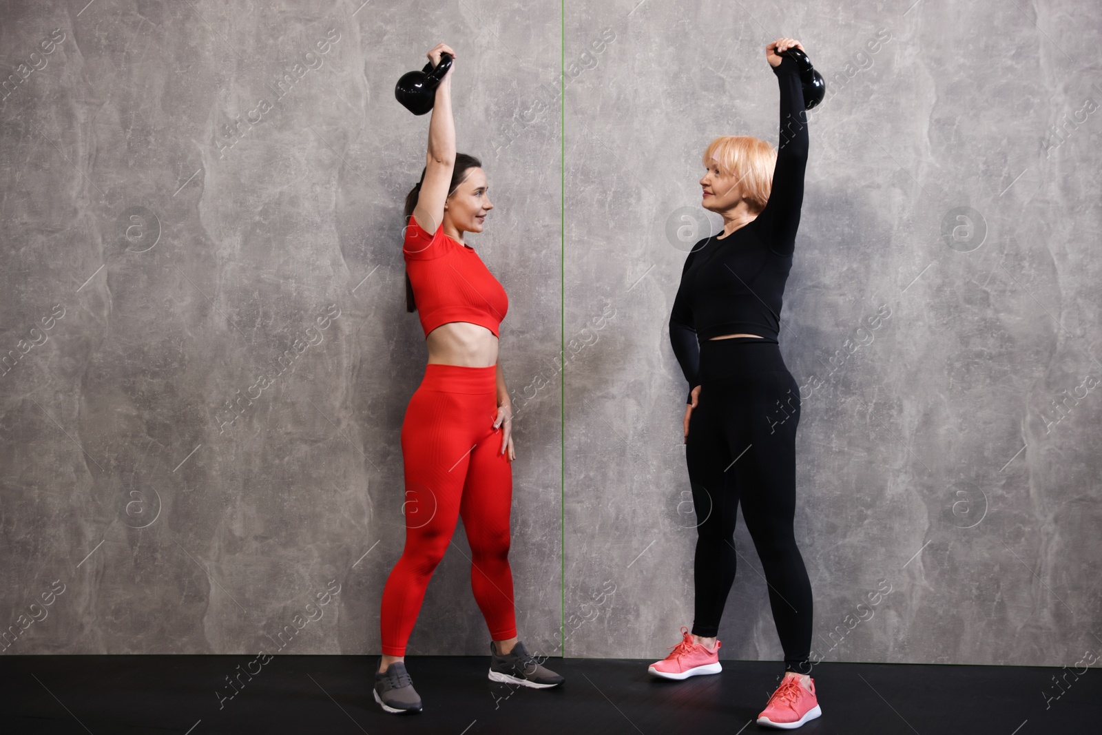 Senior woman and professional trainer training with kettlebells in gym Photo of Senior woman and professional trainer training with kettlebells in gym