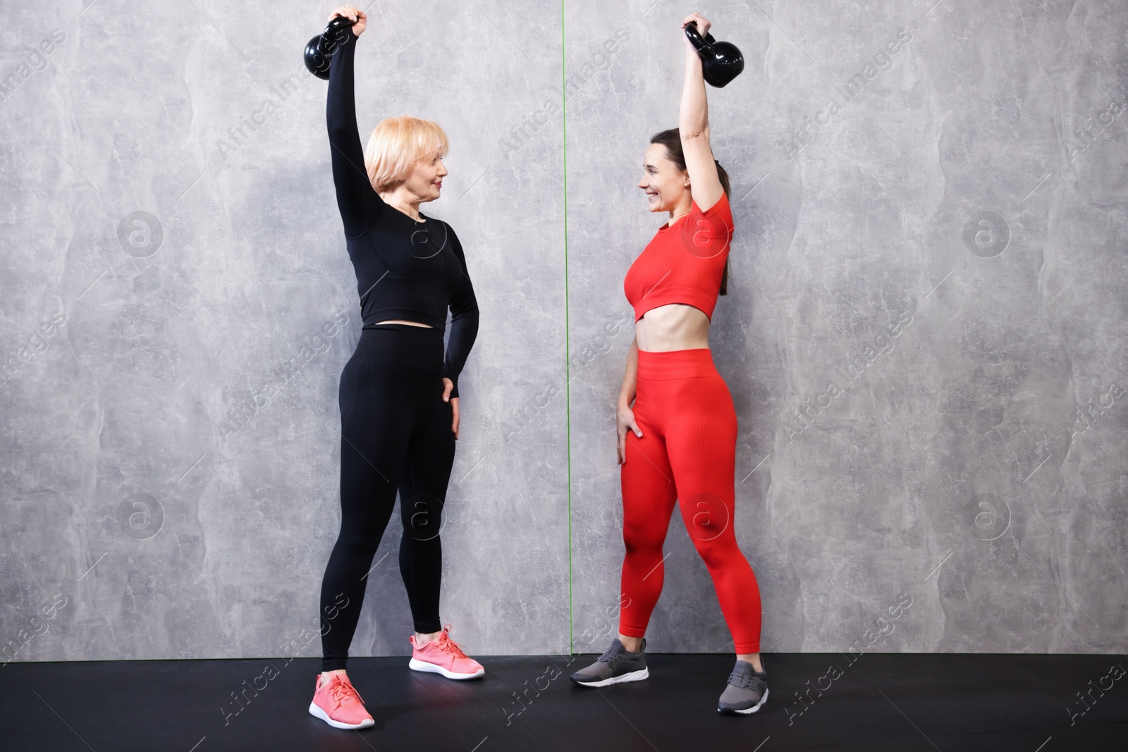 Senior woman and professional trainer training with kettlebells in gym Photo of Senior woman and professional trainer training with kettlebells in gym