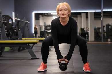 Photo of Senior woman training with kettlebell in gym