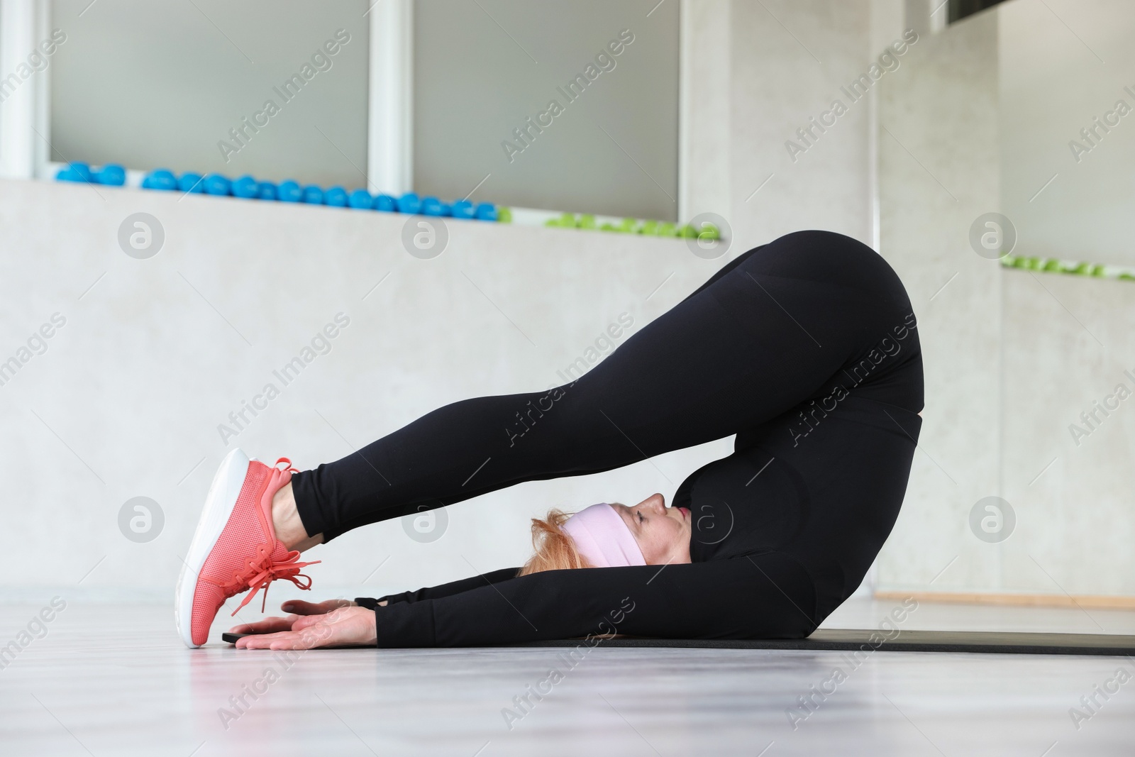 Senior woman exercising on fitness mat in gym Photo of Senior woman exercising on fitness mat in gym
