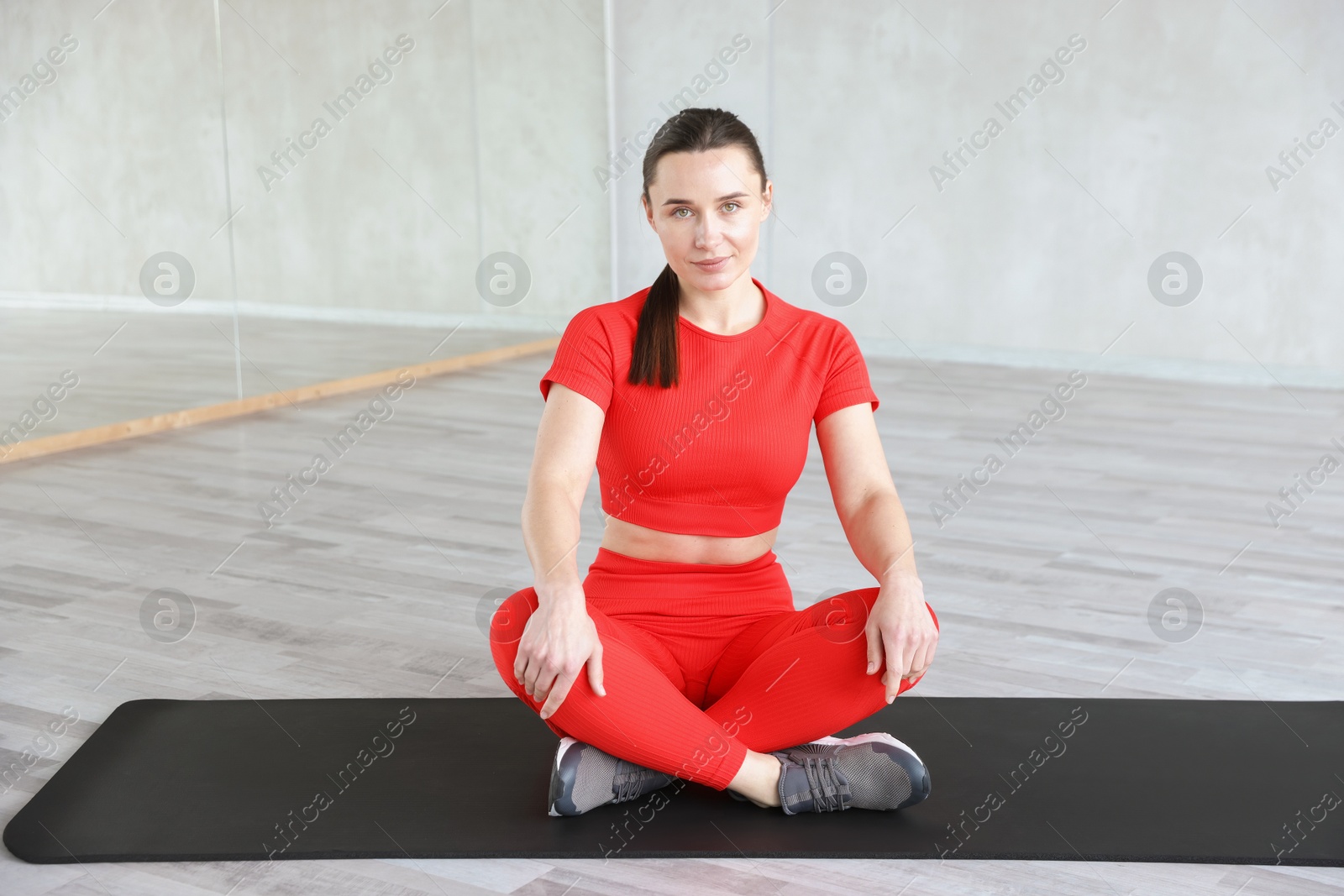 Beautiful woman sitting on fitness mat in gym Photo of Beautiful woman sitting on fitness mat in gym