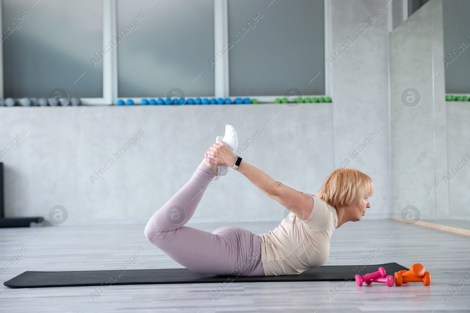 Senior woman exercising on fitness mat in gym Photo of Senior woman exercising on fitness mat in gym