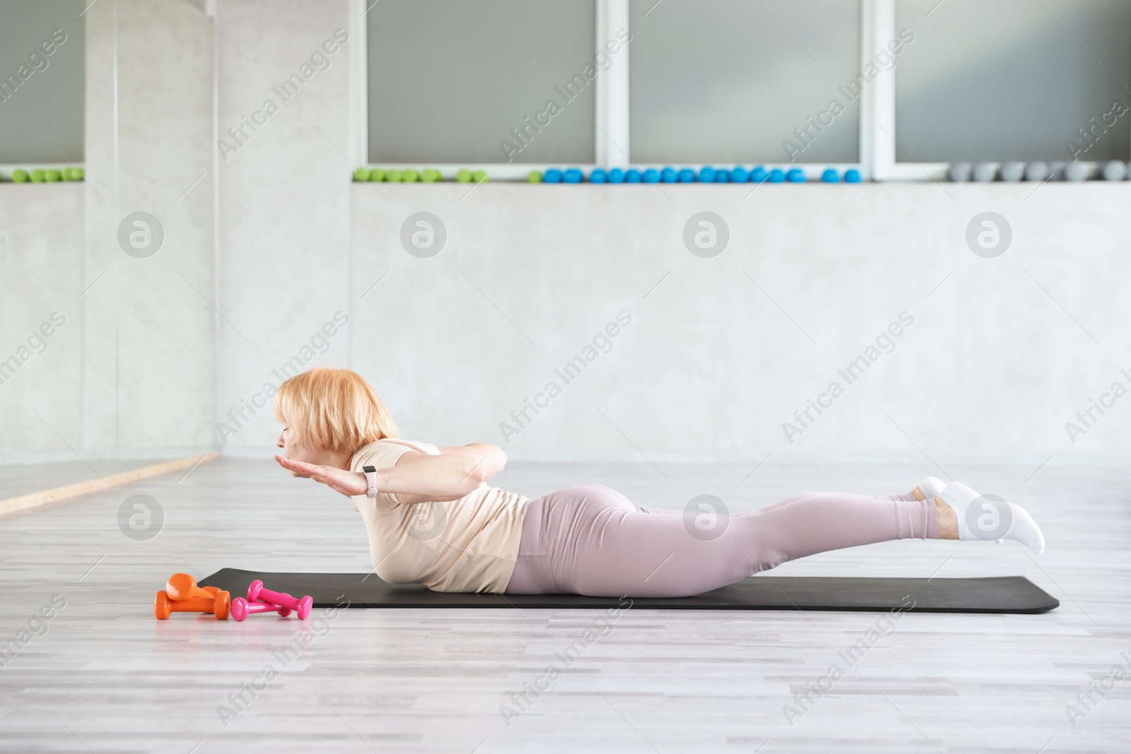 Senior woman exercising on fitness mat in gym Photo of Senior woman exercising on fitness mat in gym