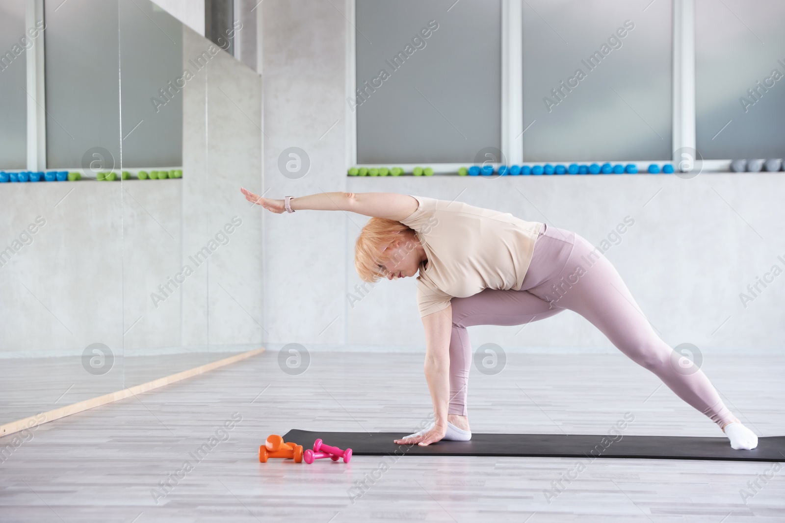 Senior woman exercising on fitness mat in gym Photo of Senior woman exercising on fitness mat in gym