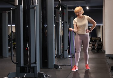 Photo of Senior woman exercising with fitness elastic band in gym
