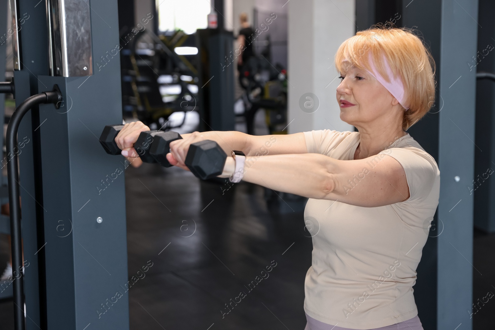 Senior woman training with dumbbells in gym Photo of Senior woman training with dumbbells in gym