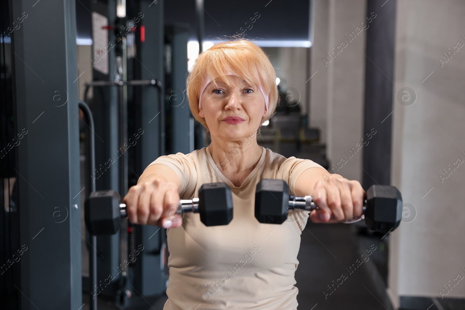 Senior woman training with dumbbells in gym Photo of Senior woman training with dumbbells in gym