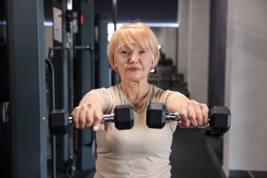 Photo of Senior woman training with dumbbells in gym