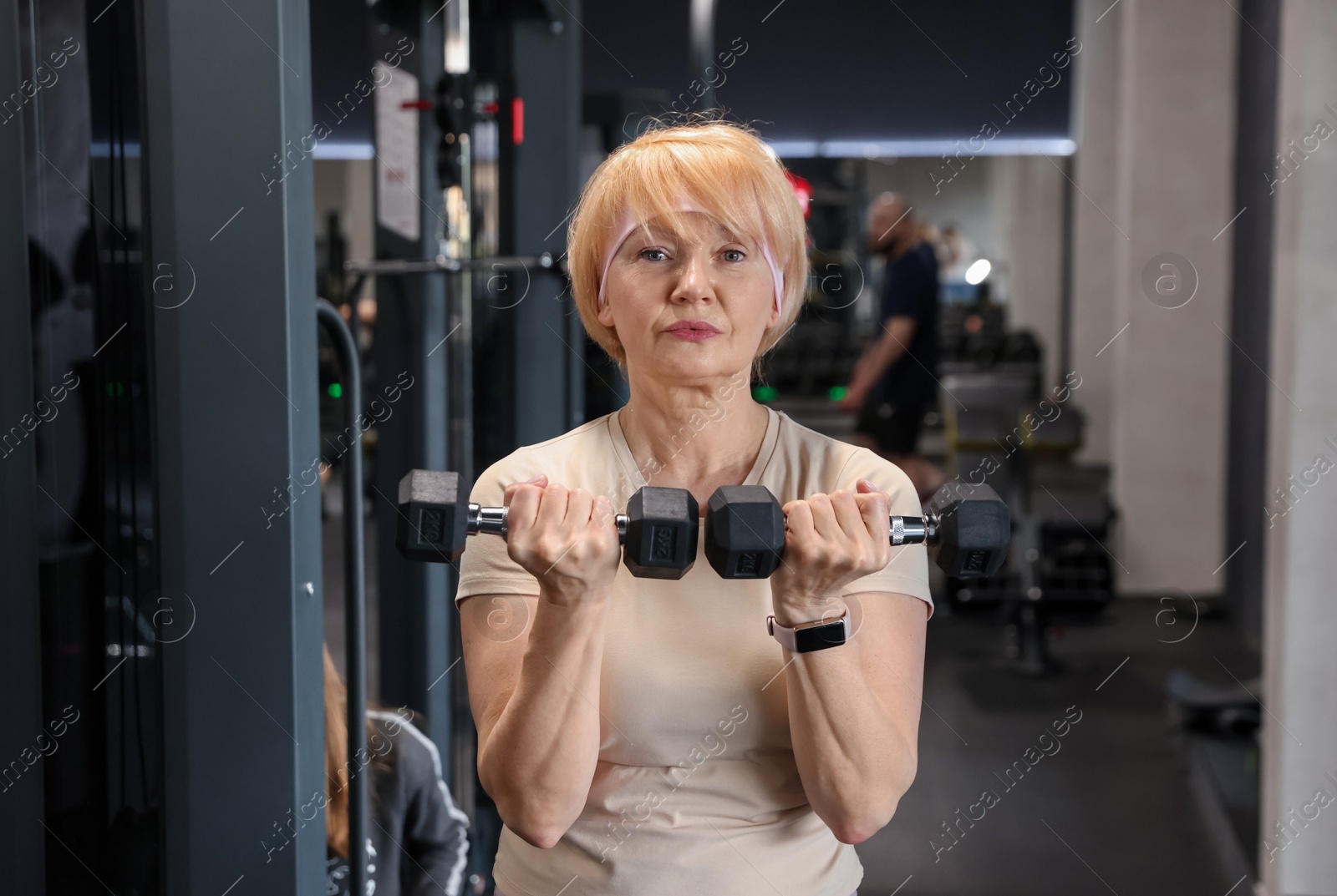 Senior woman training with dumbbells in gym Photo of Senior woman training with dumbbells in gym
