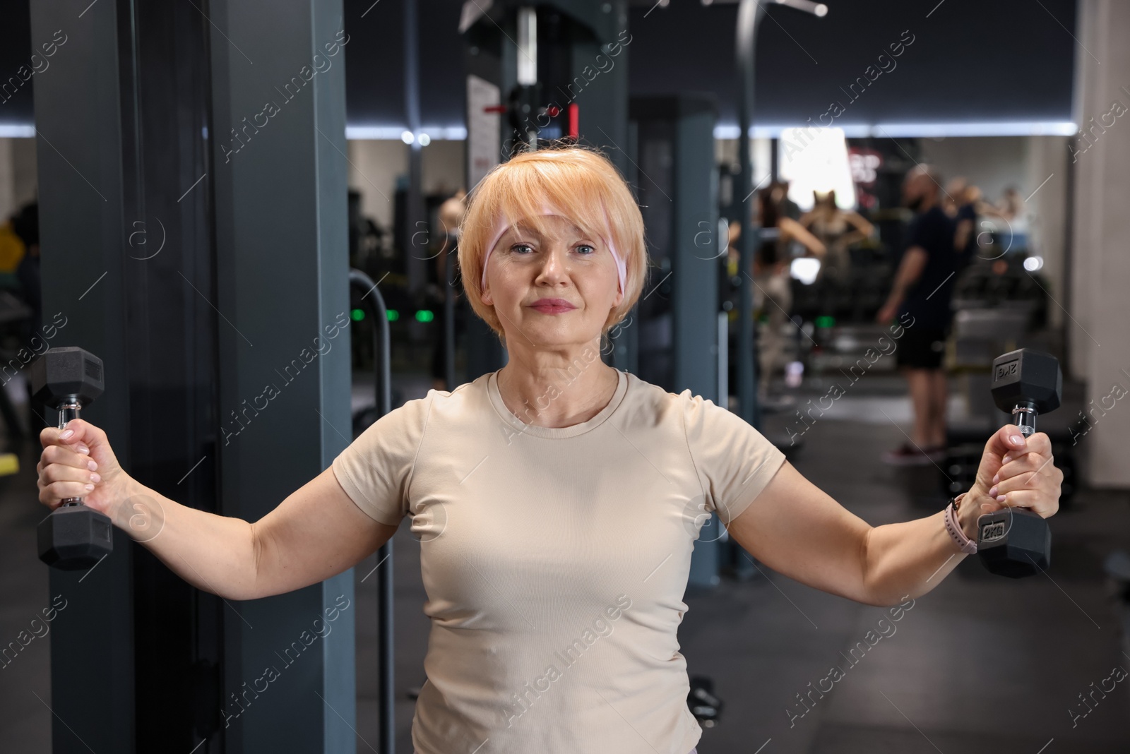 Senior woman training with dumbbells in gym Photo of Senior woman training with dumbbells in gym