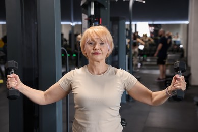 Photo of Senior woman training with dumbbells in gym