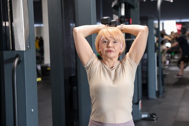 Photo of Senior woman training with dumbbells in gym