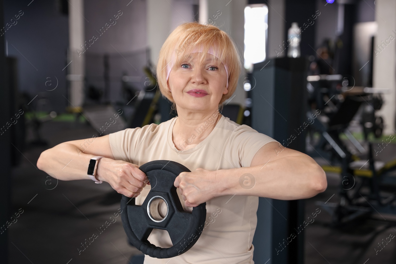 Senior woman training with weight plate in gym Photo of Senior woman training with weight plate in gym