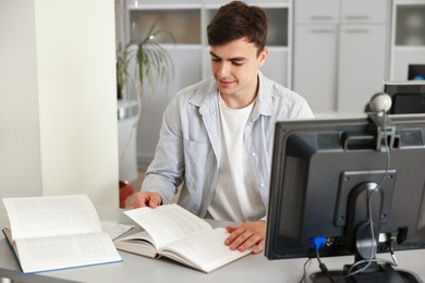 Photo of Man reading book at desk in public library
