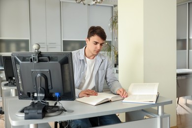 Photo of Man reading book at desk in public library