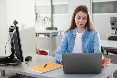 Photo of Woman working with laptop at desk in public library