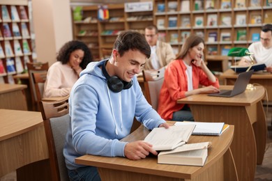 Photo of People studying at desks in public library, selective focus
