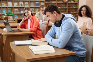 Photo of People studying at desks in public library, selective focus