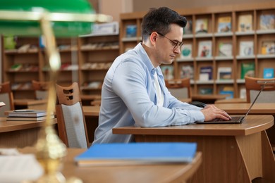 Photo of Man working on laptop at desk in public library
