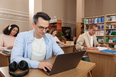 Photo of People studying at desks in public library, selective focus