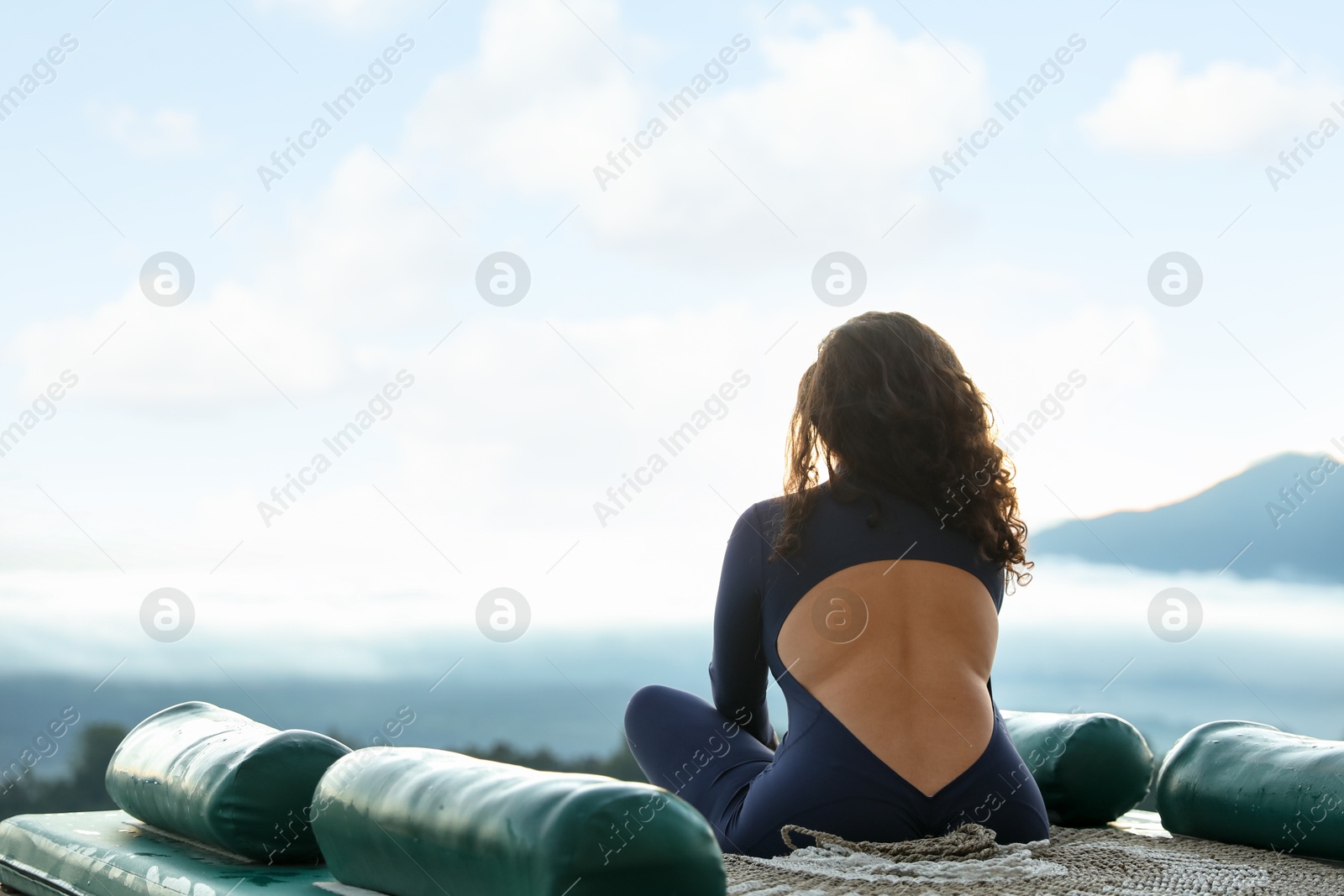 Woman meditating on mat in mountains, back view. Space for text Photo of Woman meditating on mat in mountains, back view. Space for text