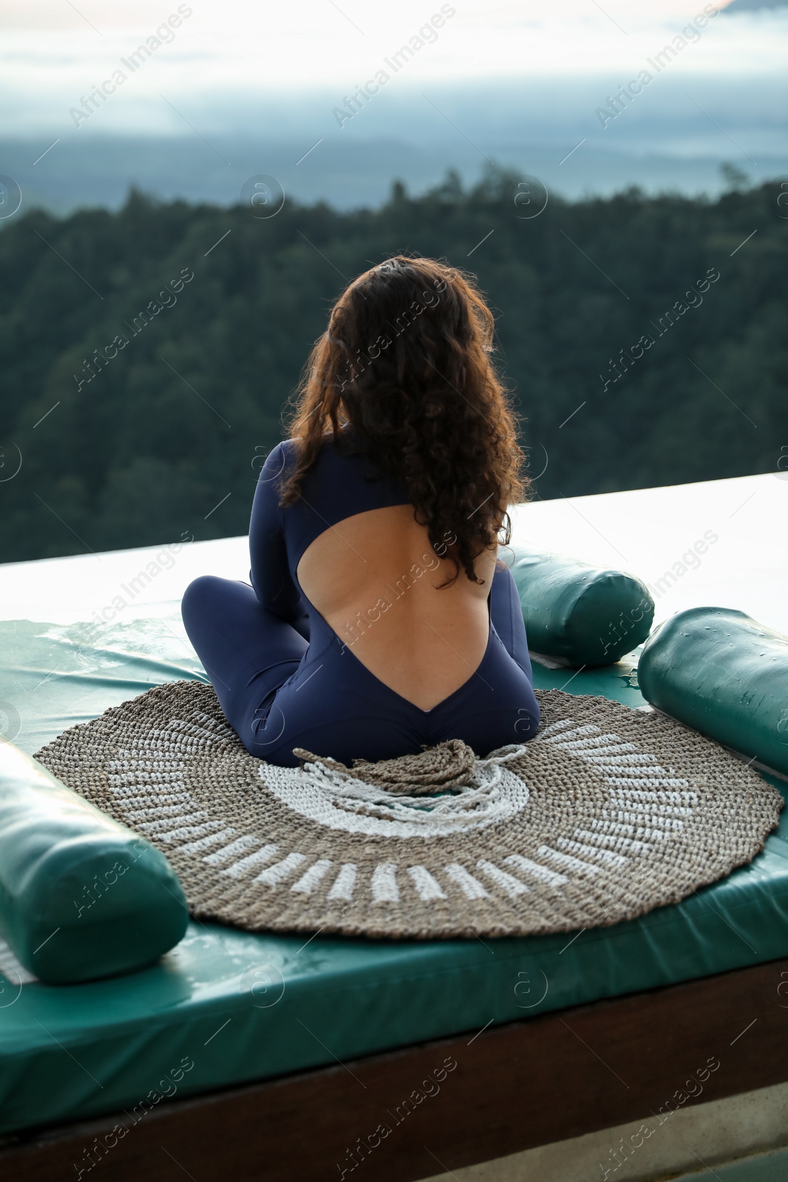 Woman meditating on mat in mountains, back view Photo of Woman meditating on mat in mountains, back view