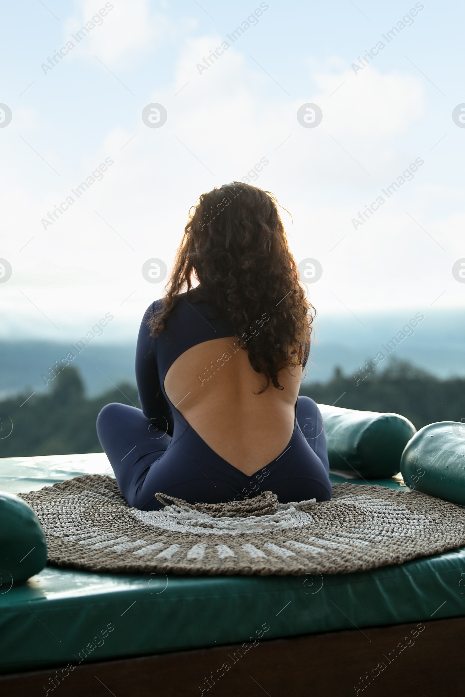 Woman meditating on mat in mountains, back view Photo of Woman meditating on mat in mountains, back view