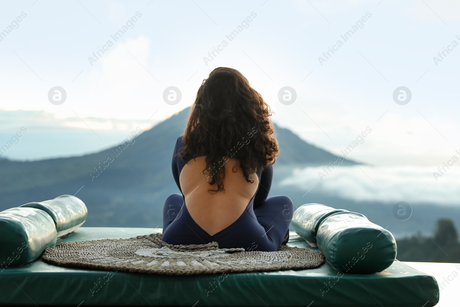 Woman meditating on mat in mountains, back view Photo of Woman meditating on mat in mountains, back view