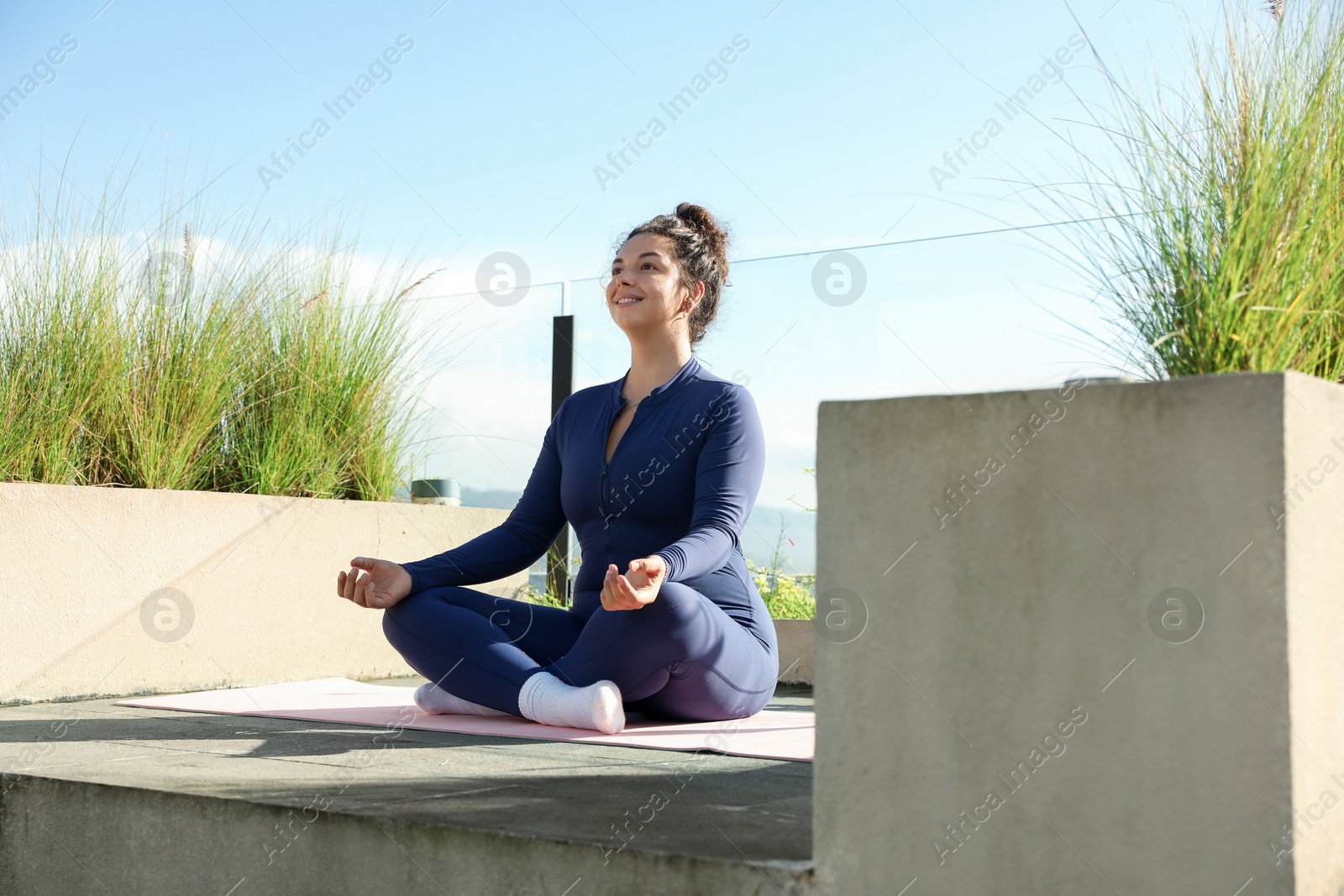 Photo of Woman meditating on yoga mat at balcony