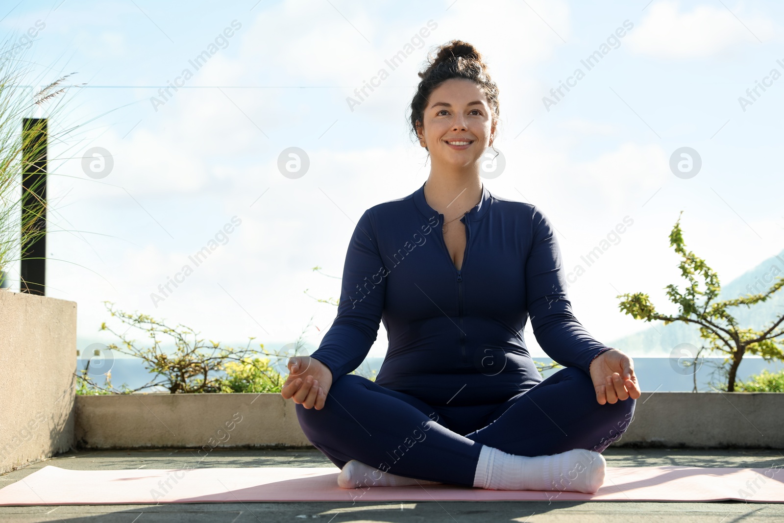 Woman meditating on yoga mat at balcony Photo of Woman meditating on yoga mat at balcony