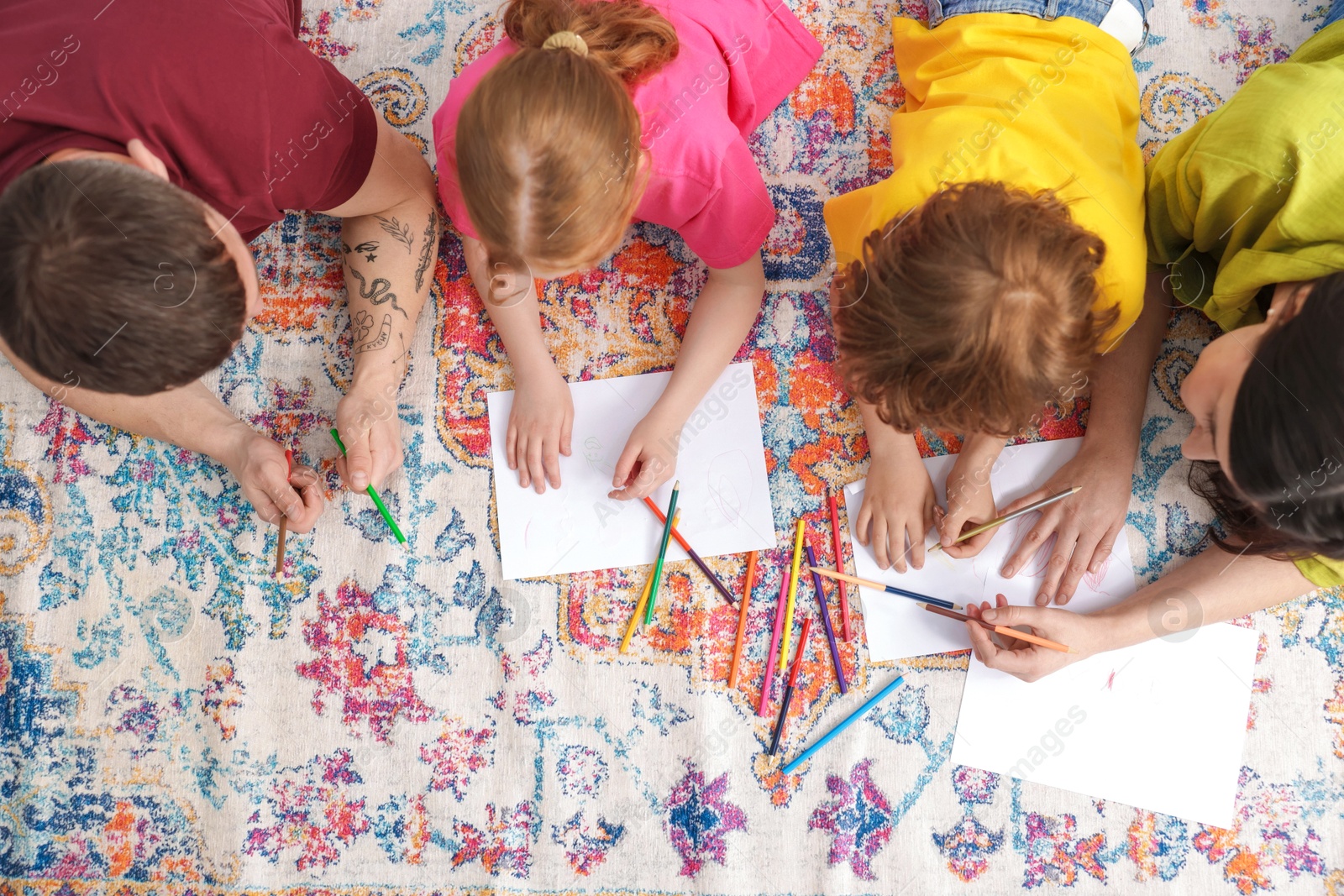 Photo of Parents teaching their kids to draw on floor at home, top view
