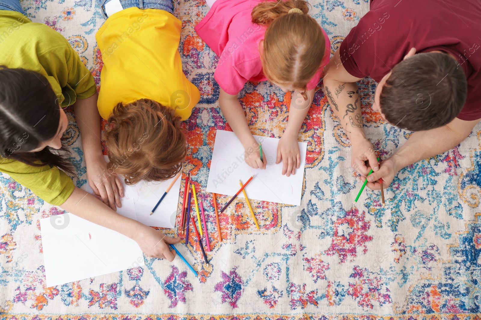 Photo of Parents teaching their kids to draw on floor at home, top view