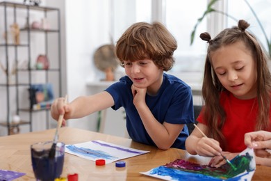 Photo of Kids painting at table indoors. Learning to draw