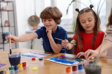 Photo of Kids painting at table indoors. Learning to draw