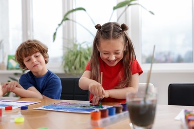 Photo of Kids painting at table indoors. Learning to draw