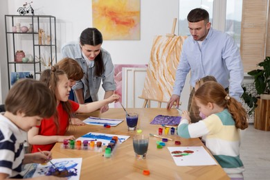 Photo of Kids with teachers at painting lesson indoors. Learning to draw