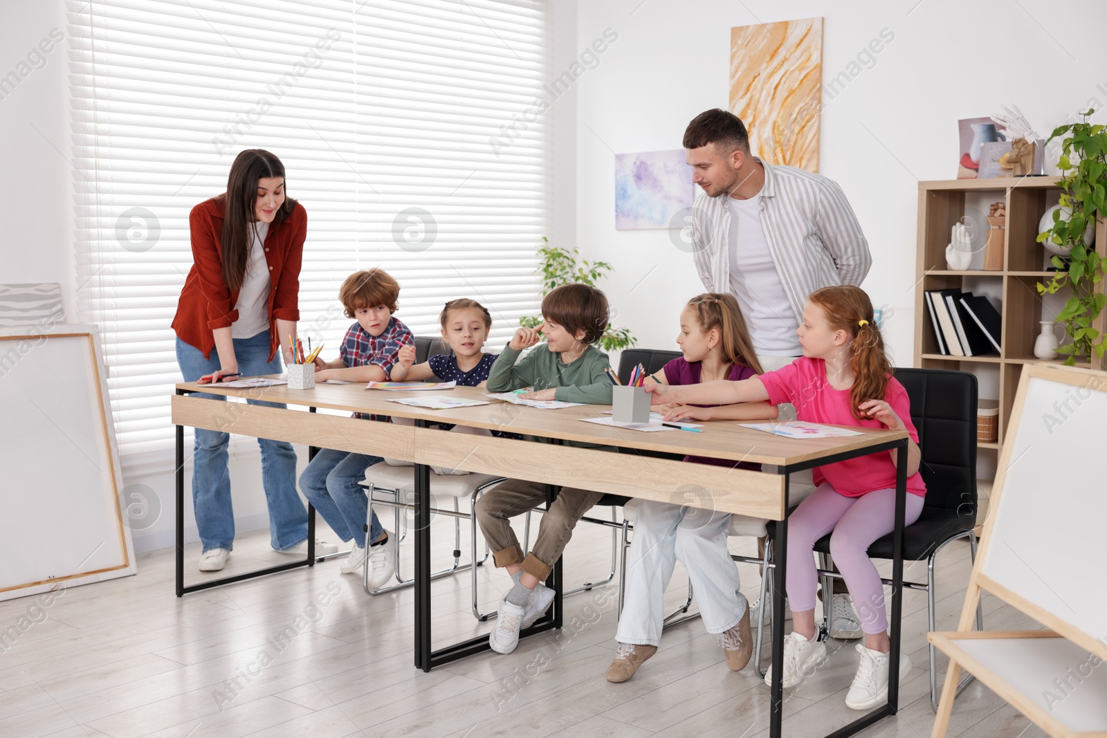 Photo of Kids with teachers at painting lesson indoors. Learning to draw