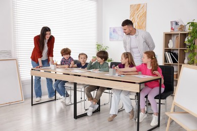 Photo of Kids with teachers at painting lesson indoors. Learning to draw
