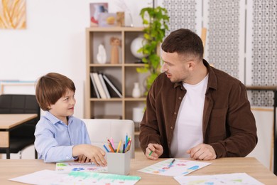 Photo of Man teaching kid to draw at painting lesson indoors