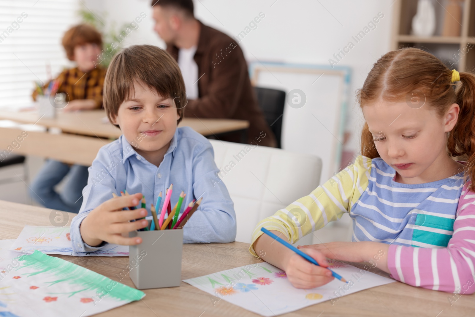 Kids with teacher at painting lesson indoors, selective focus. Learning to draw Photo of Kids with teacher at painting lesson indoors, selective focus. Learning to draw