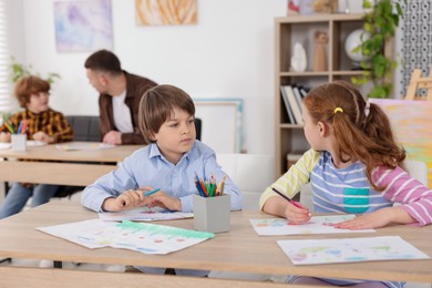 Photo of Kids with teacher at painting lesson indoors, selective focus. Learning to draw