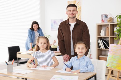 Photo of Kids with teachers at painting lesson indoors, selective focus. Learning to draw