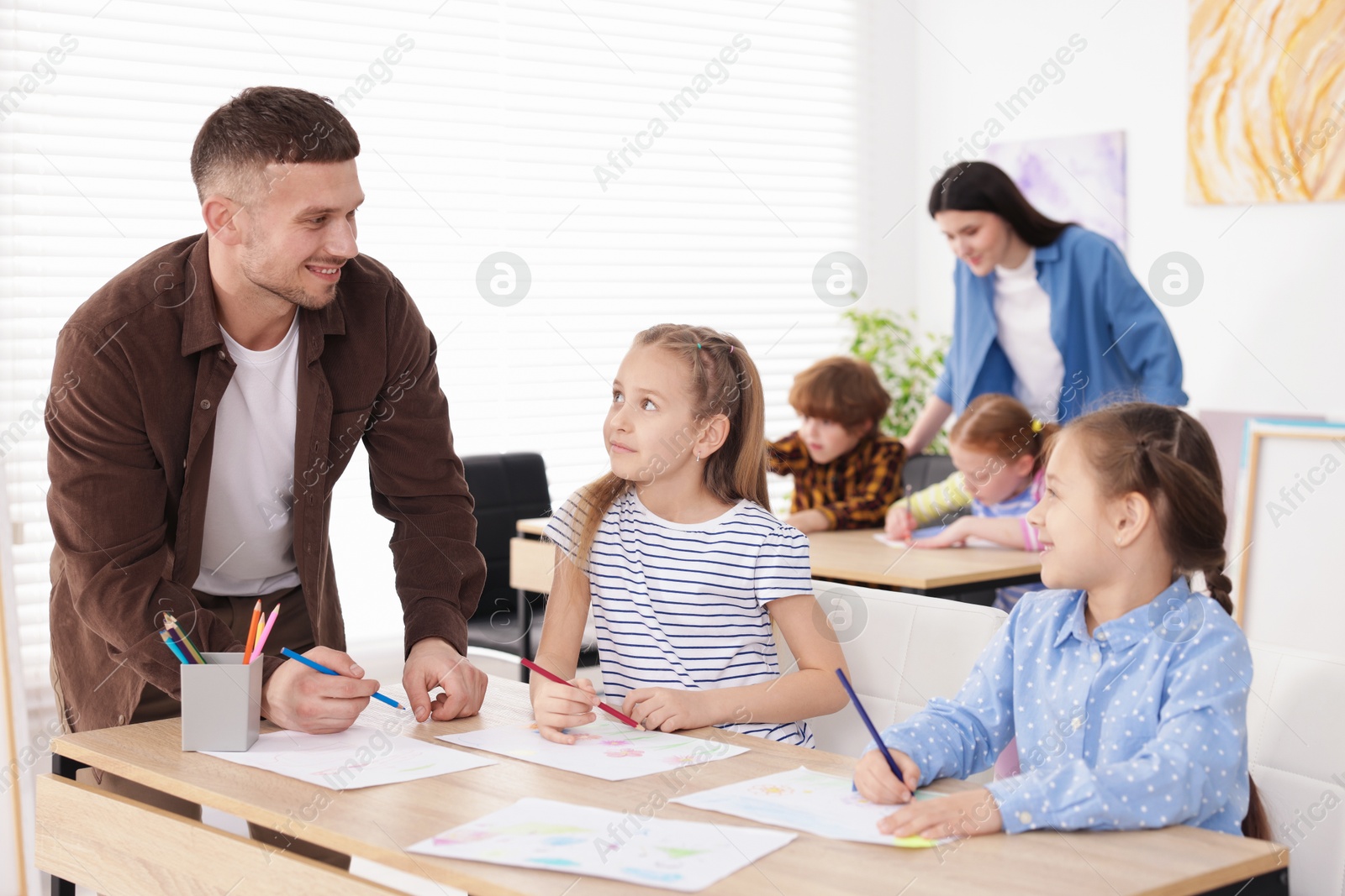 Photo of Kids with teachers at painting lesson indoors, selective focus. Learning to draw