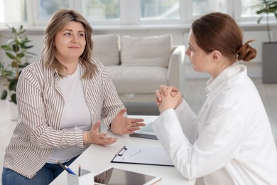 Photo of Weight loss. Nutritionist consulting overweight woman at white desk in clinic